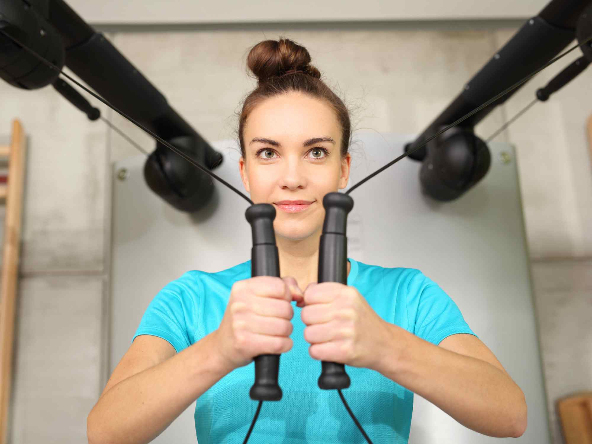 Woman performing shoulder rehabilitation exercises with resistance bands in a fitness studio